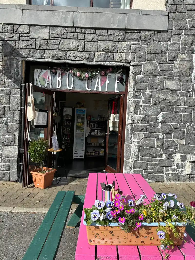 Kabo Cafe stone entrance with pink picnic table and flower boxes