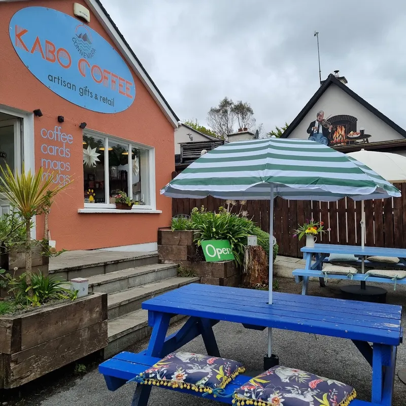 Outdoor seating at Kabo Coffee with blue picnic tables and striped umbrella